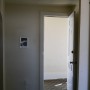 view from bedroom doorway of apartment entry door in living room at building hallway