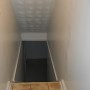 view of basement stairway through hallway from rear entrance